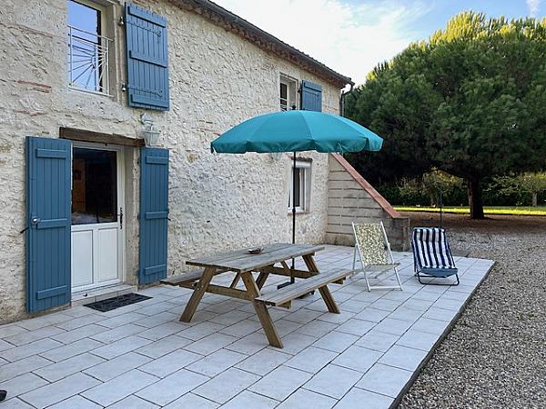 back patio with picnic table and blue umbrella