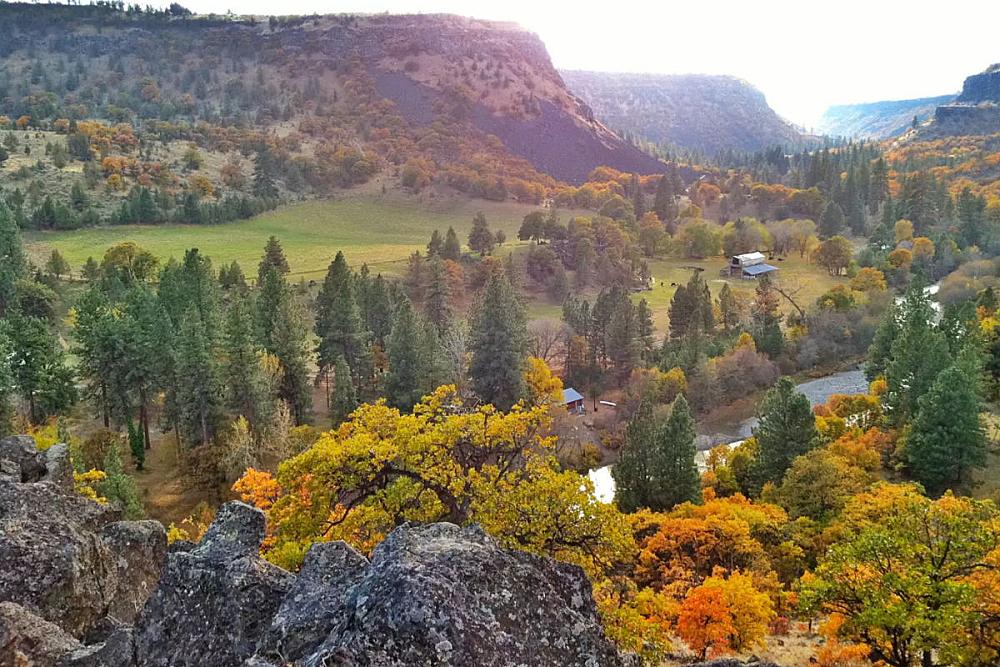 Featured Image - aerial view down a valley with a river and a distant barn
