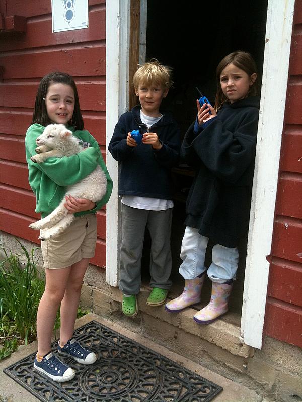 Children standing in a doorway with one of them holding a lamb