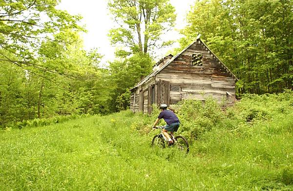 Person cycling through a field and by a cabin at Sweet Retreat Guesthouse and Sugarworks, Northfield, VT 