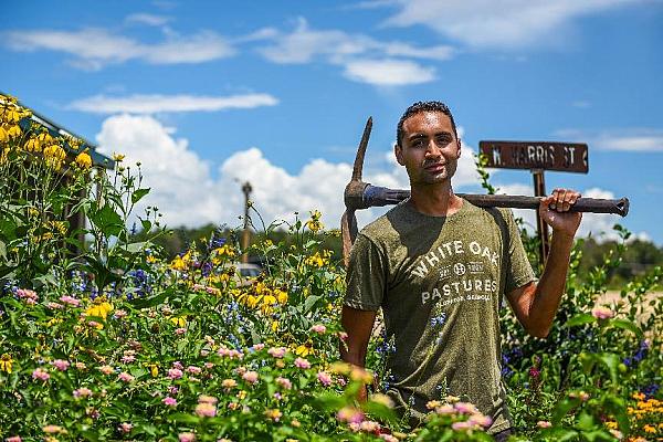 A person holding a tool in a garden of flowers at White Oak Pastures, Bluffton, Georgia 