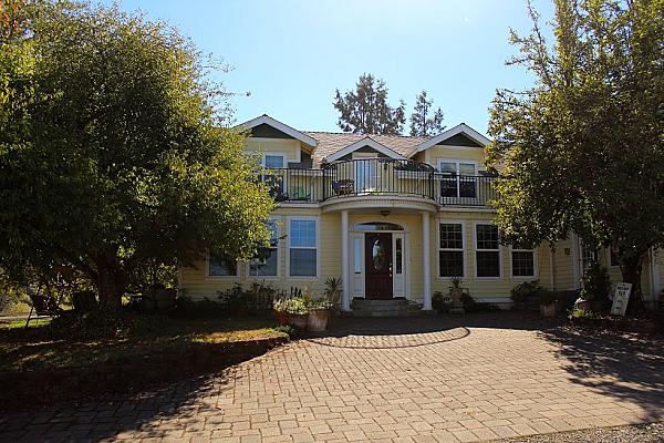 facade of yellow house with front door and brick parking area out front