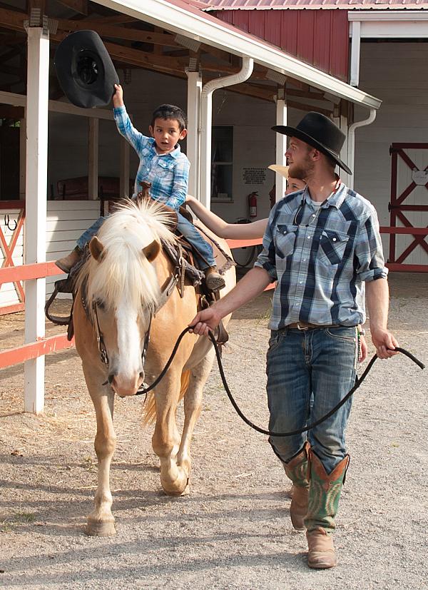 Man leading a young boy on a palomino colored horse
