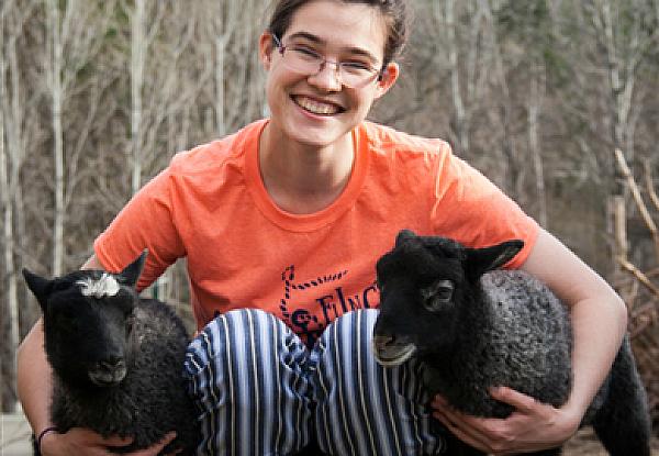 Person holding 2 lambs at Grand View Farm, Washington, Vermont 
