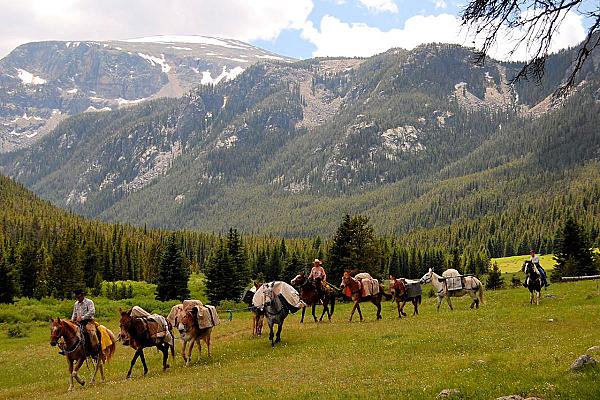 people riding horses with mountains in the background
