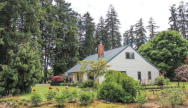 white farm house set amongst flower beds and trees