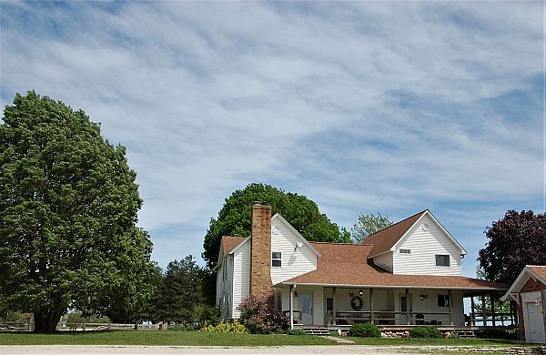 white farm house surrounded by green lawn and trees