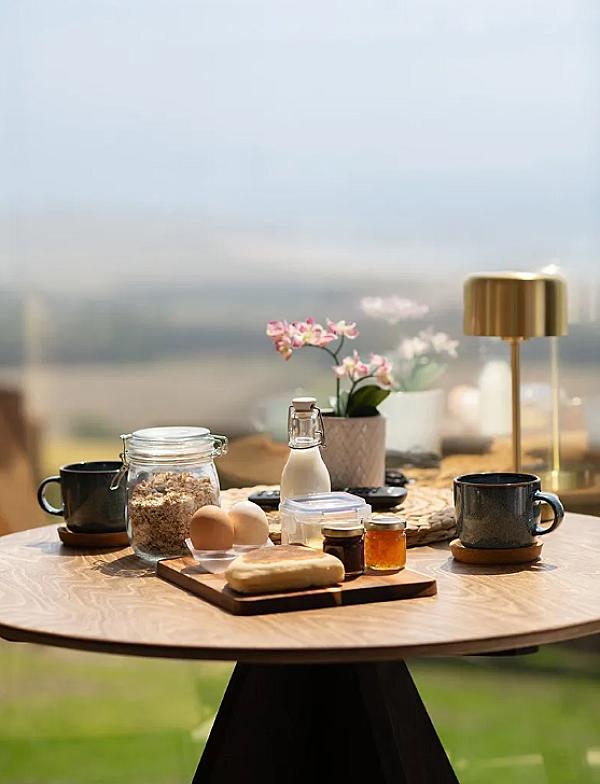 a table set up outside with fresh breakfast items, coffee, eggs, honey, flowers