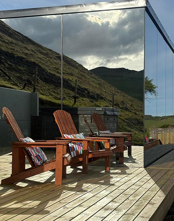 mirrored glass exterior on the pod, deck with chairs