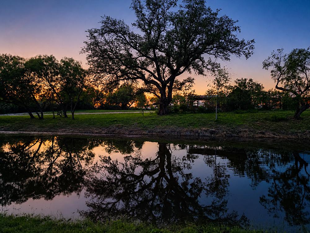 Sunset reflecting over a peaceful pond at Cherry Creek Cottages, a luxury Texas Hill Country farm stay near San Antonio