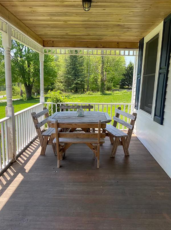 A covered front porch with tables and chairs