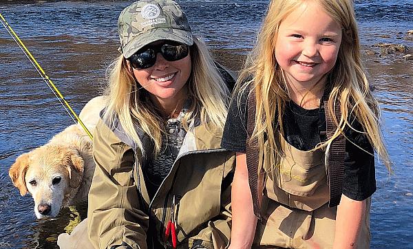 two girls fishing with dog in background