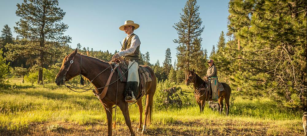 Featured Image- People horseback riding through a field and forest
