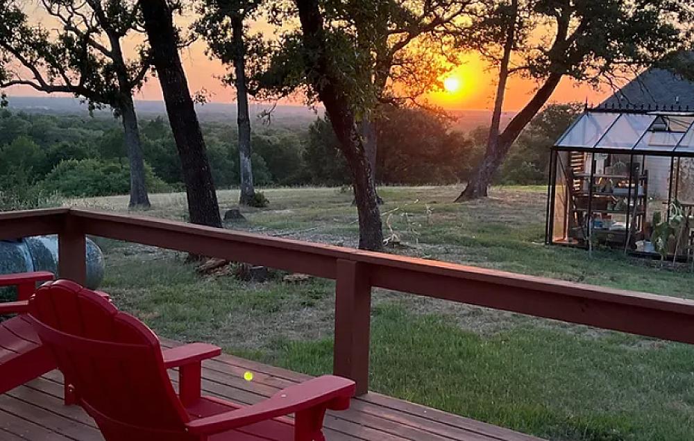 Featured Image-Chair on a deck overlooking the farm, greenhouse and gorgeous sunset