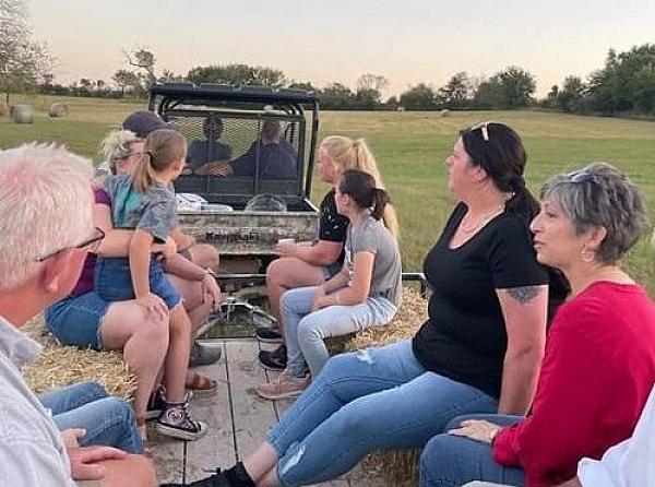 people in the back of a hay wagon being pulled by a tractor 