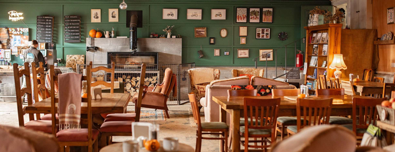 warmly lit cafe with fireplace serving with many tables and chairs
