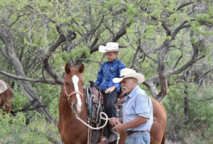 a kid riding a horse with a man leading