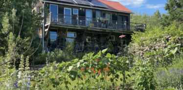 a 2 story old house with a flower garden out front