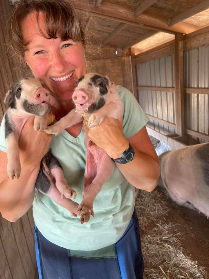 farmer holding piglets at Blooming Joy Farm