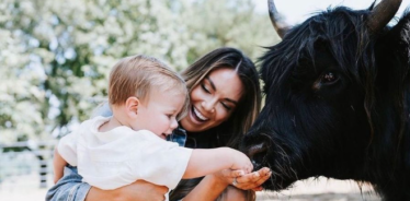 a woman and baby feeding a cow