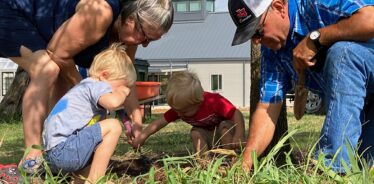 adults and kids digging in the dirt looking for worms