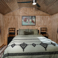 Bedroom inside Pixie's Porch Tiny Home with queen bed, two nightstands with charging stations and lots of storage.