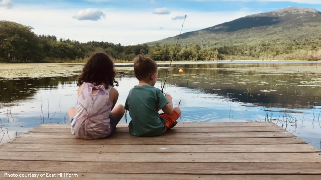 East HIll Farm- a boy and girl sitting on the dock of a pond fishing