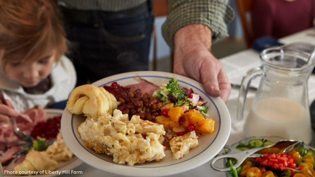 A hand holding a plate of homemade, locally grown breakfast food at Liberty Hill Farm